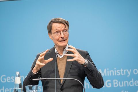 Minister Karl Lauterbach bei der Pressekonferenz vor blauem Hintergrund.