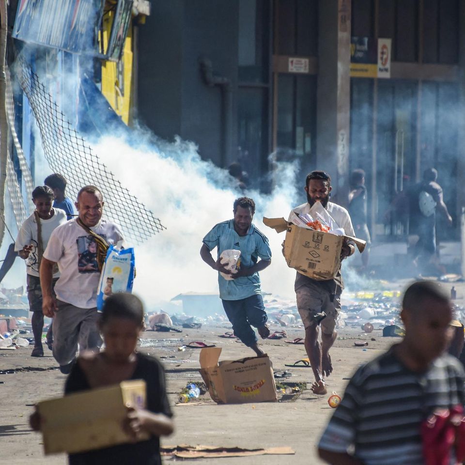 Port Moresby, Papua-Neuguinea. Menschen plündern Geschäfte, Händler versuchen zu retten, was zu retten ist. Hintergrund der Unruhen ist ein schwelender Gehaltsstreit zwischen den Sicherheitskräften Papua-Neuguineas, der jetzt in wütenden Protesten mündet.
