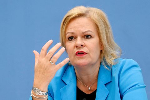 Innenministerin Nancy Faeser gestikuliert vor einer blauen Wand.