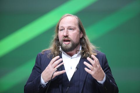 Anton Hofreiter gestikuliert vor grünem Hintergrund.