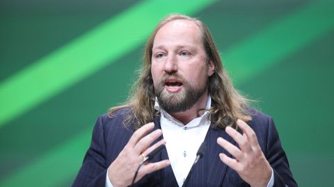 Anton Hofreiter gestikuliert vor grünem Hintergrund.