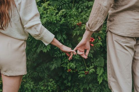 Micro-Flirten: eine Frau und ein Mann halten sich an den kleinen Fingern fest