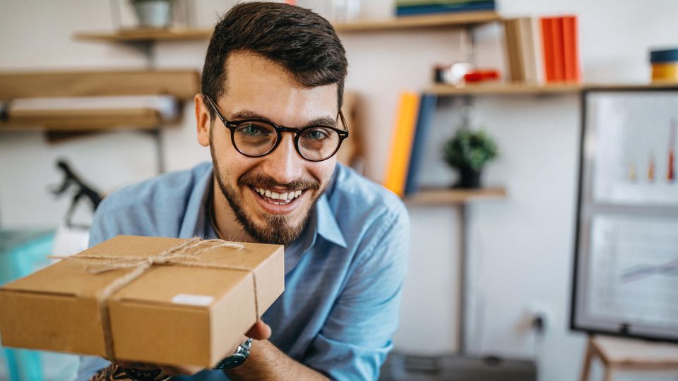 Foto eines jungen Mannes mit einem Paket im Büro