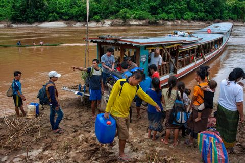 Menschen steigen aus einem Boot am Fluss Mekong