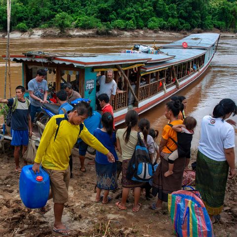 Menschen steigen aus einem Boot am Fluss Mekong