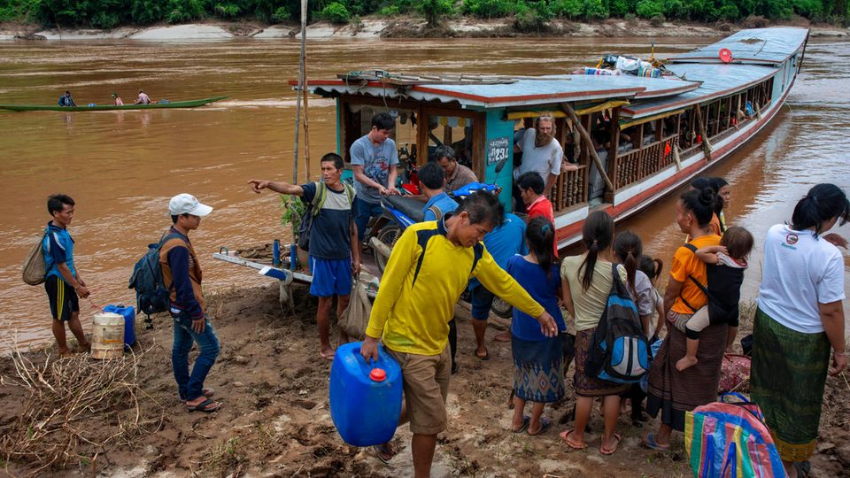 Menschen steigen aus einem Boot am Fluss Mekong
