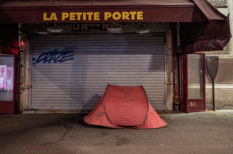 Das orange Zelt eines Obdachlosen steht in Paris vor dem heruntergelassenen Rollladen eines Geschäfts