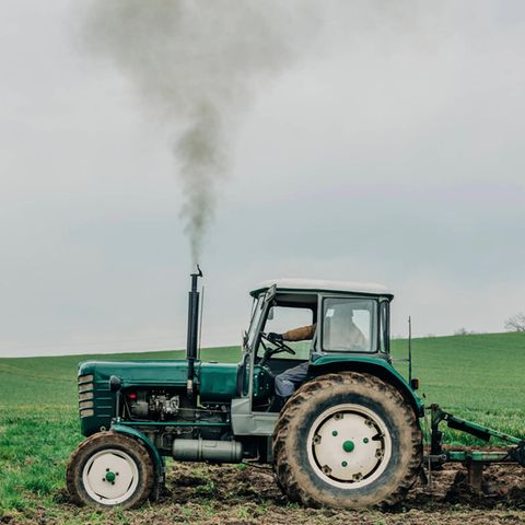 Ein Traktor fährt über ein Feld und bläst dabei Treibstoff in die Luft