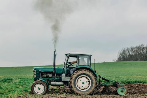 Ein Traktor fährt über ein Feld und bläst dabei Treibstoff in die Luft