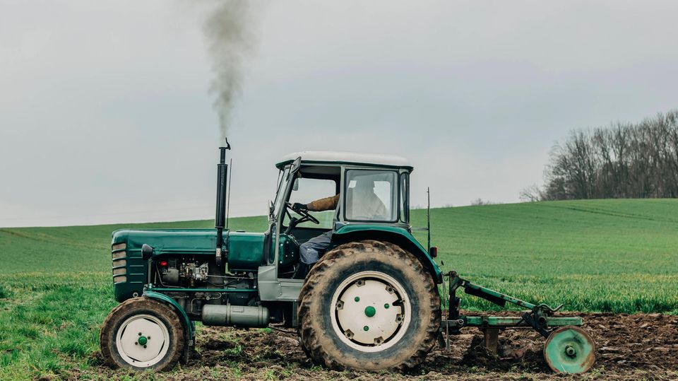 Ein Traktor fährt über ein Feld und bläst dabei Treibstoff in die Luft