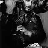 Ein Kämpfer der palästinensischen Fatah steht mit seiner Waffe in der Hand und einem Patronen-Gürtel neben anderen trauernden