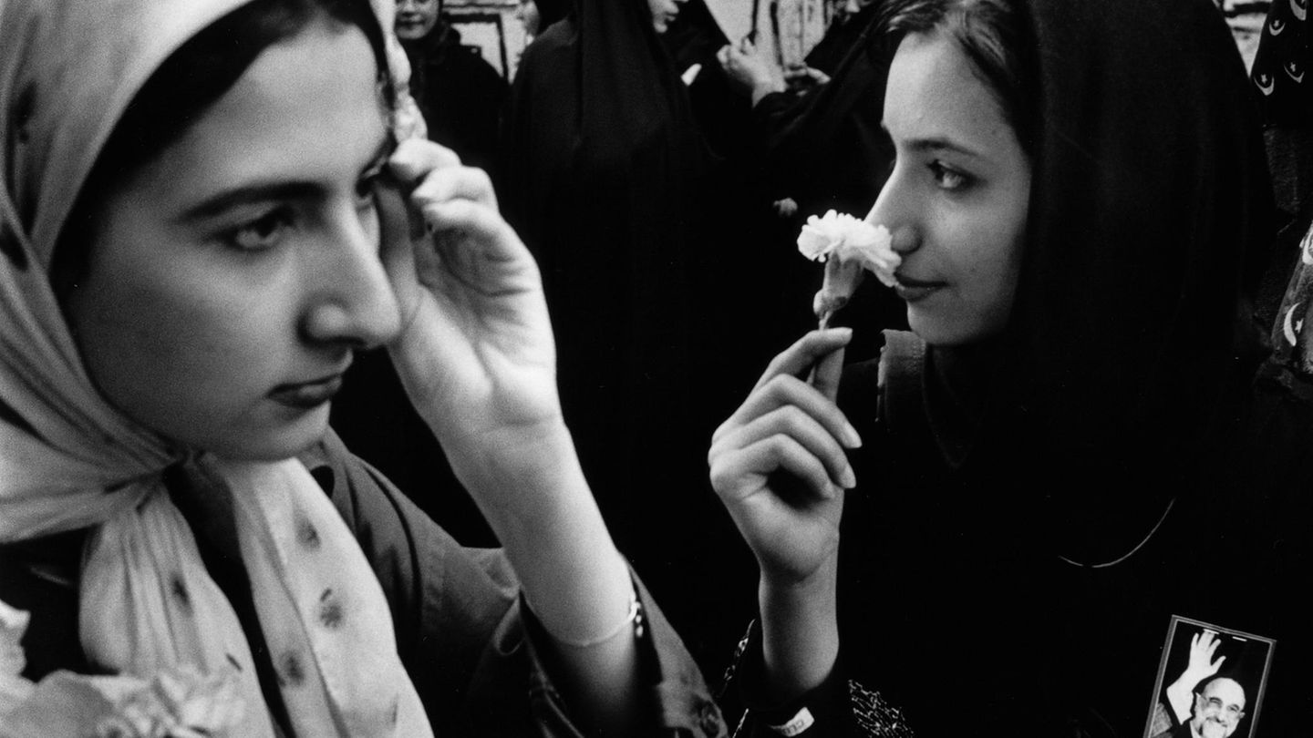 Teheran: Zwei Junge Frauen mit Kopftüchtern in Iran, die eine riecht an einer weißen Blume