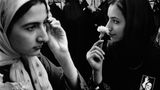 Teheran: Zwei Junge Frauen mit Kopftüchtern in Iran, die eine riecht an einer weißen Blume