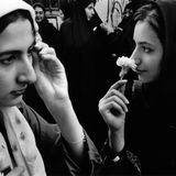 Teheran: Zwei Junge Frauen mit Kopftüchtern in Iran, die eine riecht an einer weißen Blume