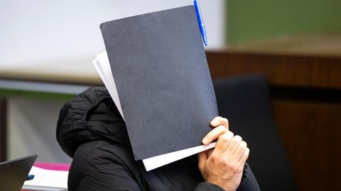 Angeklagter Münchner Trainer hält sich Mappe vors Gesicht