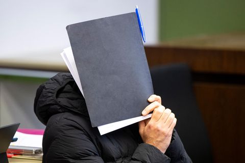 Angeklagter Münchner Trainer hält sich Mappe vors Gesicht