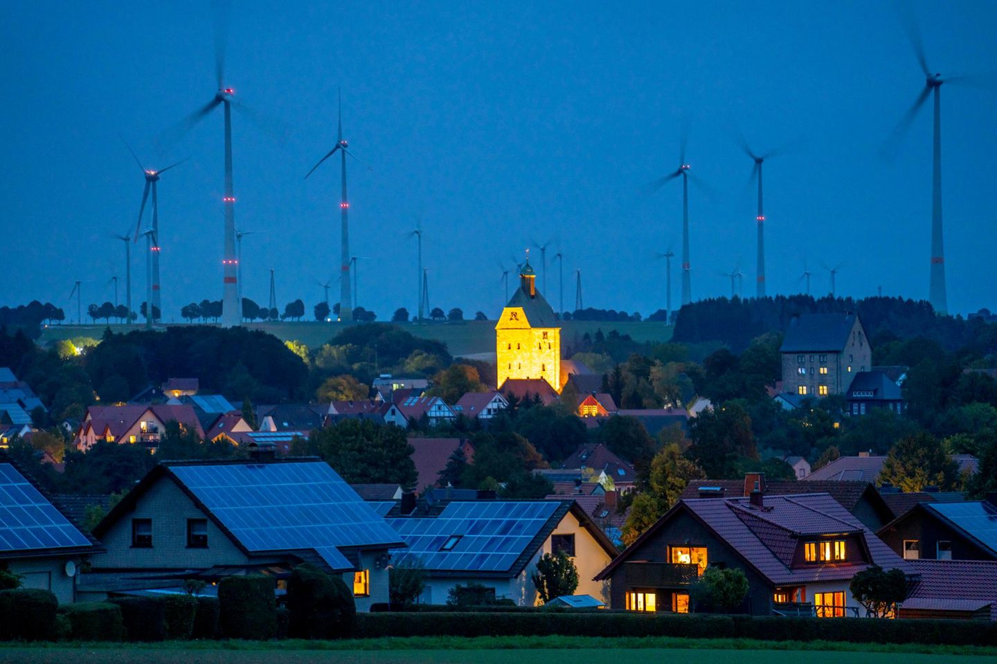 Kleinstadt in der Abenddämmerung mit Solardächern und Windpark