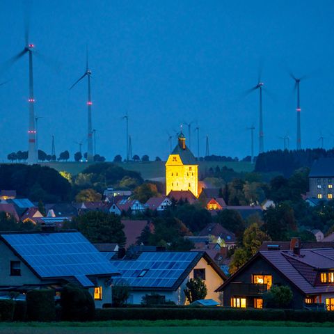 Kleinstadt in der Abenddämmerung mit Solardächern und Windpark
