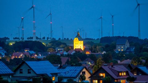 Kleinstadt in der Abenddämmerung mit Solardächern und Windpark