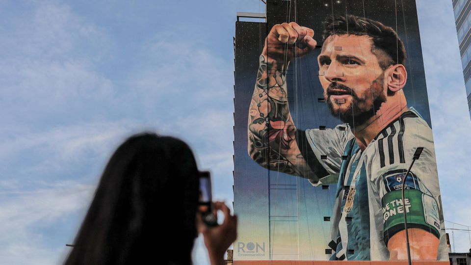 Lionel Messi als Bild auf einer Hauswand, eine Frau fotografiert ihn.