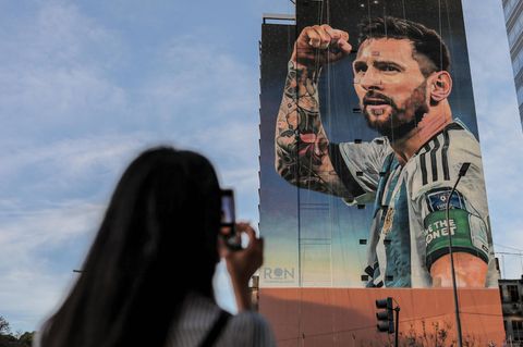 Lionel Messi als Bild auf einer Hauswand, eine Frau fotografiert ihn.