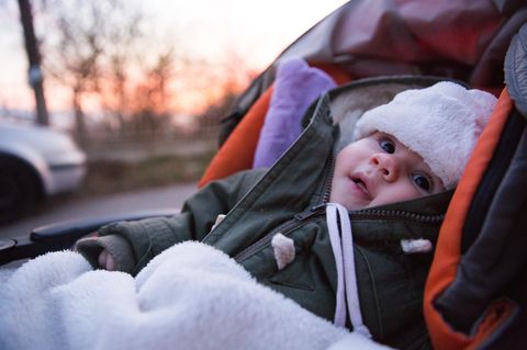 Lammfell im Kinderwagen: Kleinkind liegt mit Fußsack in Kinderwagen