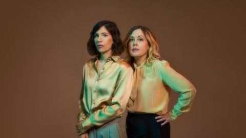 Portrait der Band Sleater-Kinney, zwei Frauen in glänzenden Blusen stehen nebeneinander