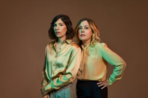Portrait der Band Sleater-Kinney, zwei Frauen in glänzenden Blusen stehen nebeneinander