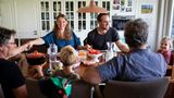 Die Familie nimmt sich bei Tisch an die Hände