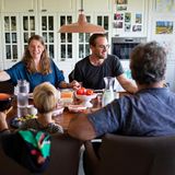 Die Familie nimmt sich bei Tisch an die Hände