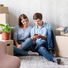Umzug: Pärchen schaut beim Packen auf das Smartphone und zieht um