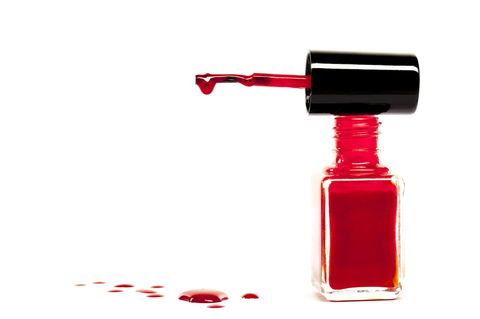 Eine offene, rote Nagellackflasche auf weißem Hintergrund