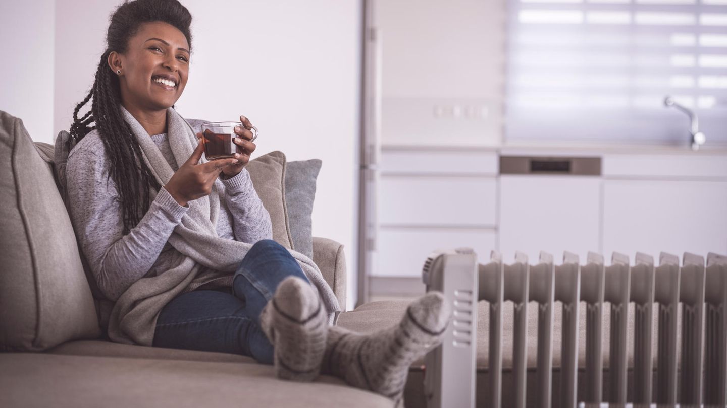 Frau nutzt einen Heizlüfter zum Aufwärmen.