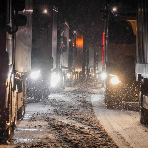 Lastkraftwagen stauen sich auf der Autobahn A5 bei Grünberg auf schneebedeckter Fahrbahn