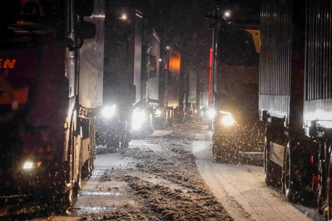 Lastkraftwagen stauen sich auf der Autobahn A5 bei Grünberg auf schneebedeckter Fahrbahn