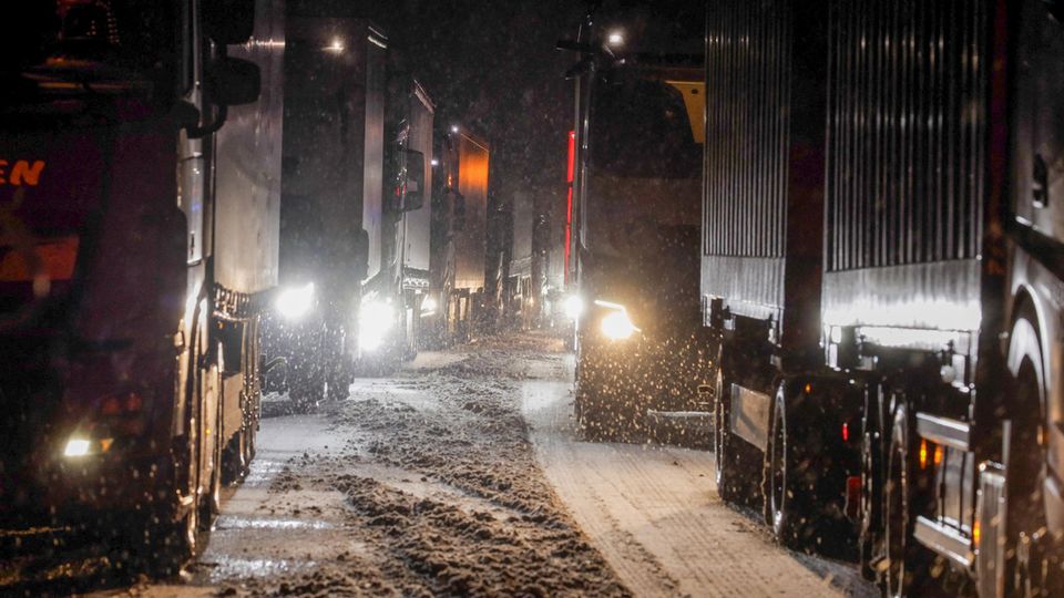 Lastkraftwagen stauen sich auf der Autobahn A5 bei Grünberg auf schneebedeckter Fahrbahn