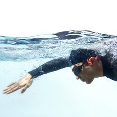 Wasserdichte Kopfhörer: Schwimmer in Neoprenanzug mit Kopfhörern
