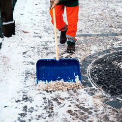 Mann streut Salz auf einem Bürgersteig