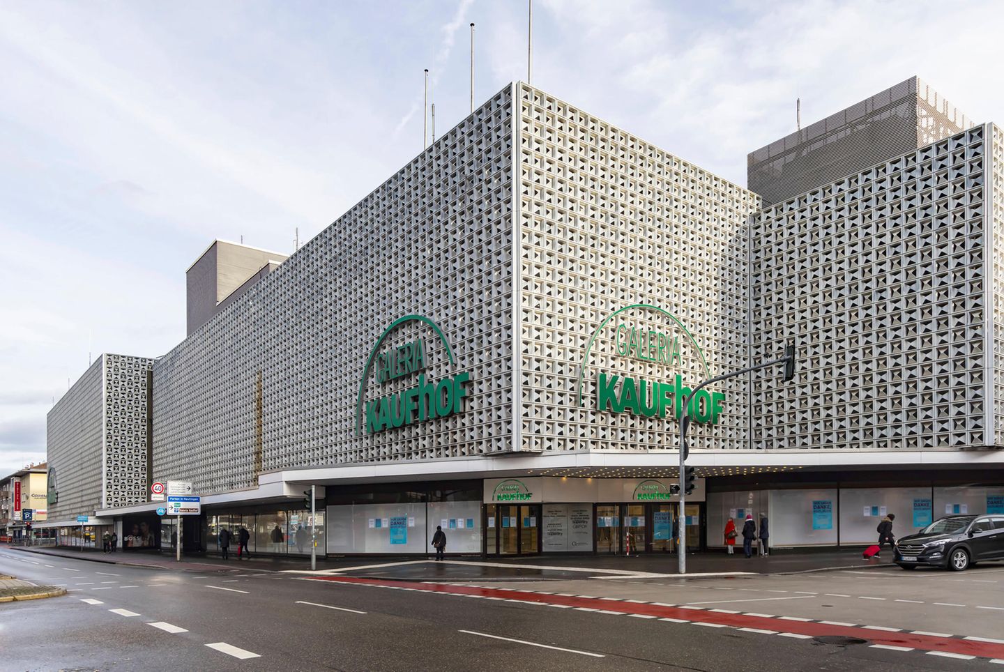 ein graues Kaufhausgebäude mit dem grünen Schriftzug des Unternehmens