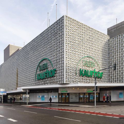 ein graues Kaufhausgebäude mit dem grünen Schriftzug des Unternehmens