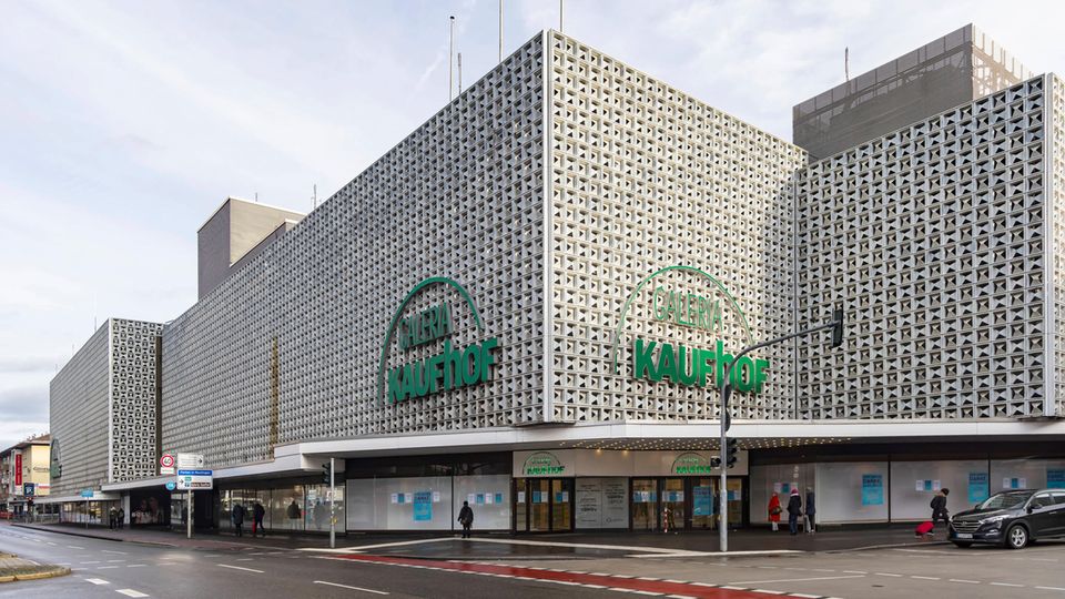 ein graues Kaufhausgebäude mit grünem Firmenschriftzug