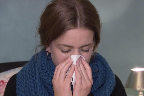 Kranke Frau, die sich die Nase putzt
