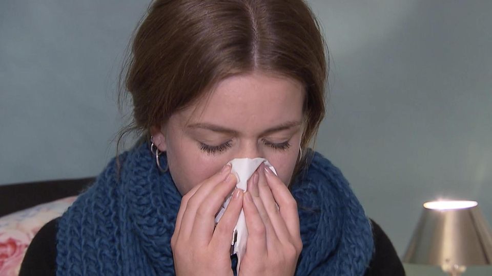 Kranke Frau, die sich die Nase putzt