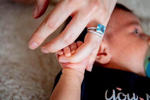 Frauenhand mit einem Ring über einem Baby