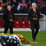 Paul Breitner (r.) und Berti Vogts legen vor Beginn der Reden Rosen am Mittelkreis ab