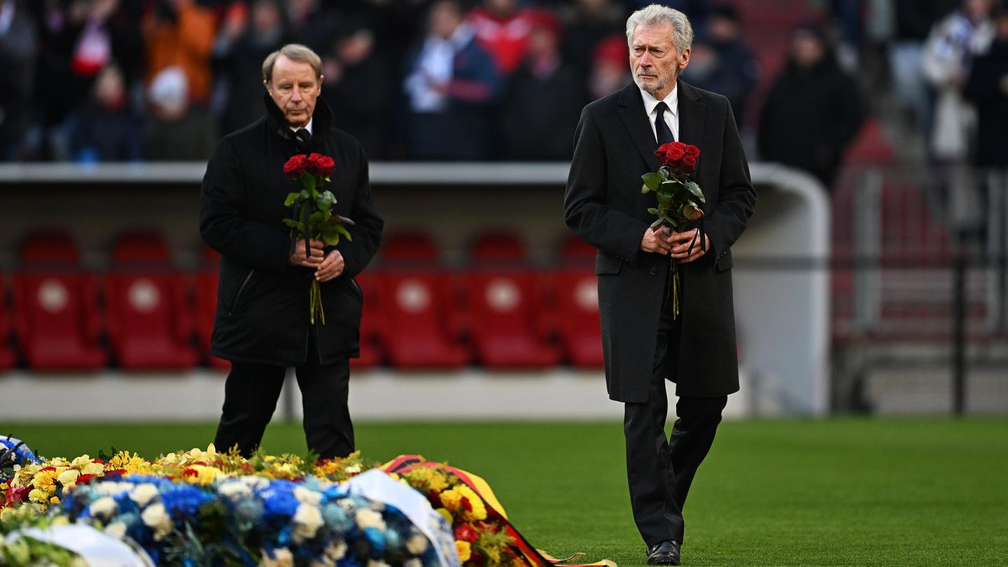 Paul Breitner (r.) und Berti Vogts legen vor Beginn der Reden Rosen am Mittelkreis ab