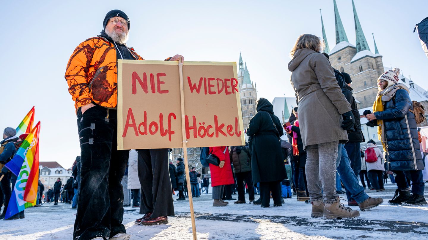 Ein Demonstrant steht am Samstag mit einem Banner mit der Aufschrift "Nie wieder Adolf Höckel" auf dem Domplatz in Erfurt