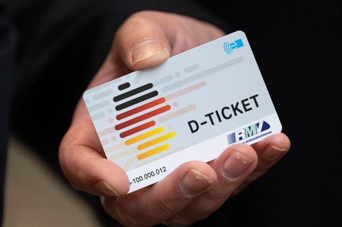 Ein Deutschlandticket in der rechten Hand eines Mannes