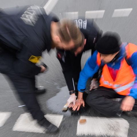 Ein Mitglied der Gruppe Letzte Generation sitzt auf der Straße