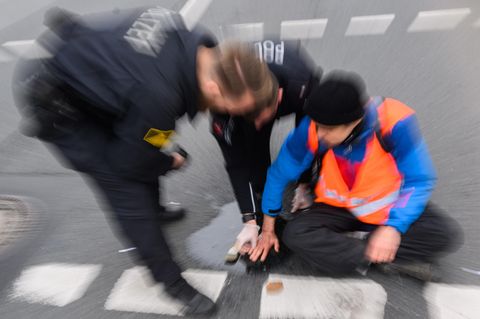Ein Mitglied der Gruppe Letzte Generation sitzt auf der Straße